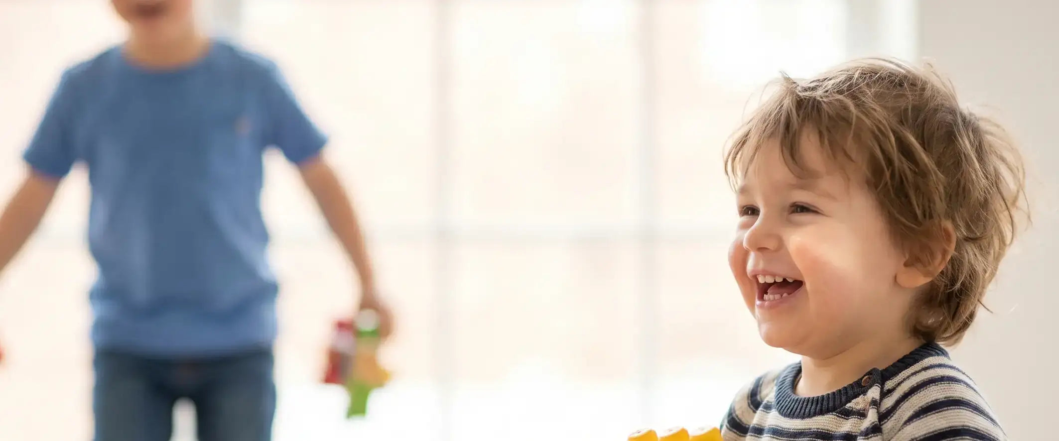 Child laughing with a blurred child in the background